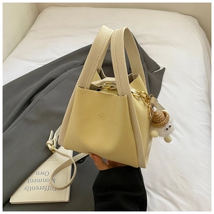 Detail of lychee textured bucket bag in yellow and cream with cute sheep plush charm