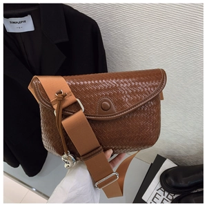 Détail du sac bandoulière marron tressé avec large sangle et pendentif cœur argenté
