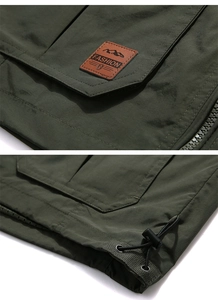 Detail of army green outdoor vest showing fashion leather patch and adjustable drawstring hem