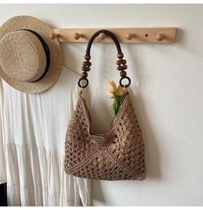 Detail of hand-woven hobo bag featuring dark brown wooden bead strap and crochet texture