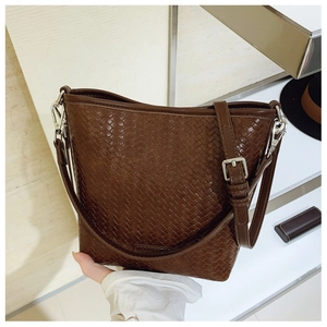 Détail du sac seau marron foncé à texture tressée avec bandoulière réglable et boucle