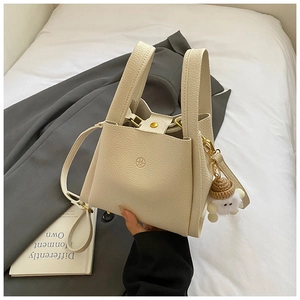 Close-up of off-white lychee grain leather bucket bag with cute sheep charm and strap