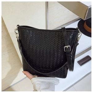 Détail de la texture tressée noire du sac seau avec boucles métalliques argentées