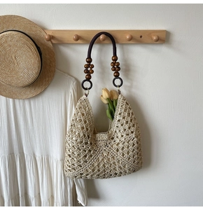 Detail of woven hobo bag featuring dark wooden bead handles and floral tulip decoration