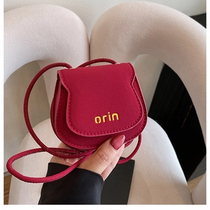 Detailed close-up of a red mini crossbody bag with yellow orin logo and slim cord strap