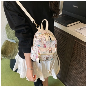 Détails d'un mini sac à dos blanc avec motifs de dessins animés et fermetures éclair dorées