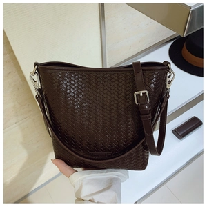 Détail de la texture tressée marron foncé d'un sac seau avec bandoulière réglable