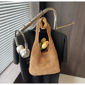 Detail of hand-woven hollow knit tote bag in retro brown hanging on a silver rack