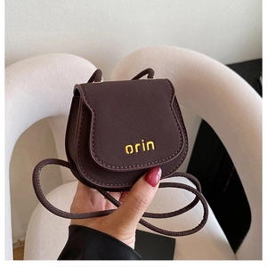 Close-up of a brown mini saddle bag with orin print and thin shoulder strap