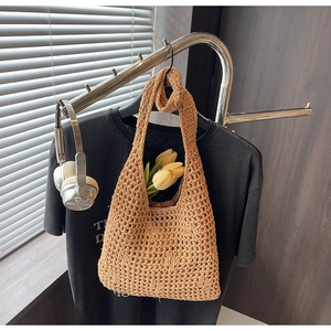 Détail du sac à bandoulière tissé avec texture ajourée sur un support métallique moderne