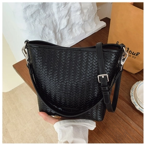 Détail du cuir tressé d'un sac seau noir avec des finitions métalliques argentées