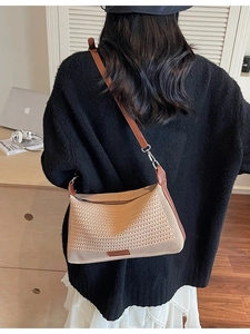 Borsa a tracolla intrecciata kaki con cinturino in pelle marrone indossata sulla spalla
