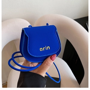 Detail view of mini Klein blue saddle bag with yellow orin text and matte PU leather texture