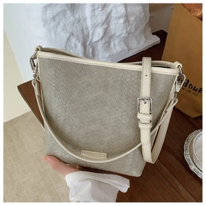 Détail de la texture tressée et bandoulière réglable sur le sac seau gris