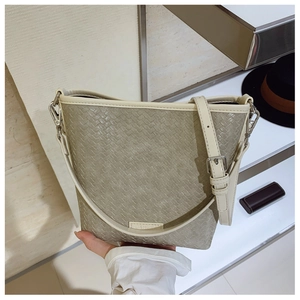 Détail du tissage sur un sac seau en tissu gris-vert avec bordures en cuir blanc chic