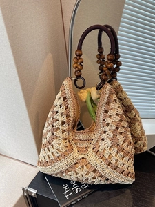 Handwoven triangle tote bag with contrast stitching and beaded wood handles in boho style
