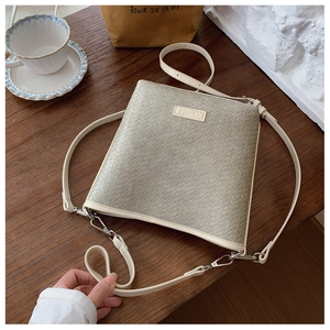 Détail du sac seau tissé vert avec bordures en cuir crème et boucles en métal argenté