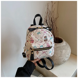 Gros plan du mini sac à dos beige avec motifs de dessins animés et lanières en cuir noir