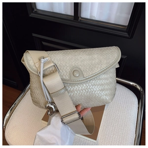 Détail du sac bandoulière tissé beige avec sangle réglable et pendentif cœur argenté