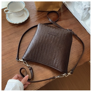 Détail de la texture tressée du sac à main marron foncé avec boucle en métal argenté