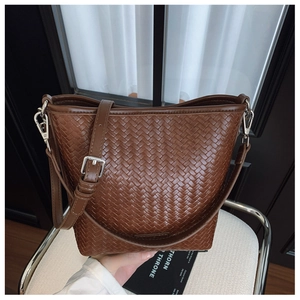 Gros plan du sac seau en cuir tressé marron foncé avec boucle en métal argenté brillant