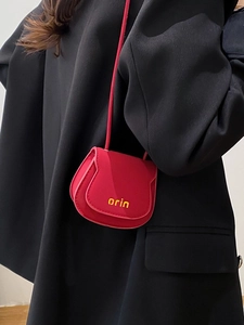 Red mini leather saddle crossbody bag with orin logo worn over a black blazer