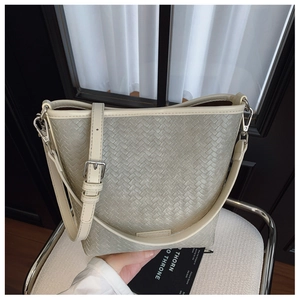 Détail du sac seau à texture tissée avec bordure crème et boucle en métal argenté