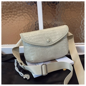 Détail du sac de poitrine tissé avec breloque cœur et bandoulière large sur livres