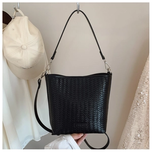 Détail du sac seau tressé noir avec texture en cuir et design à double bandoulière