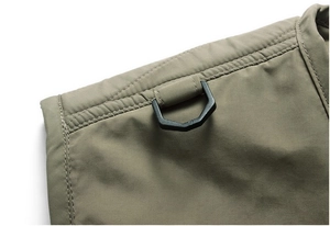 Detail of army green tactical vest featuring a durable black D-ring and high-density fabric