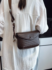 Sac bandoulière en cuir tressé marron foncé avec sangle réglable porté par un mannequin