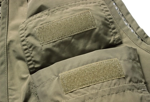 Detailed macro view of olive green tactical vest showing functional Velcro pockets