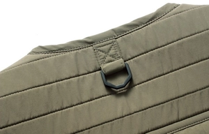 Macro detail of olive green quilted outdoor vest with reinforced hexagon D-ring attachment