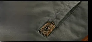 Detailed view of dark olive jacket pocket with faux leather trim and metal eyelet