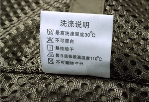 Detailed close-up of the washing instructions label on an olive green mesh fishing vest