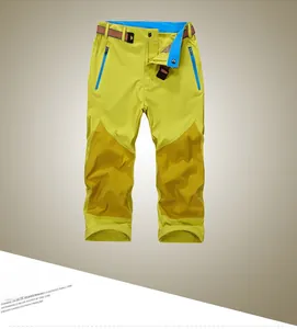 Detail of yellow quick-dry pants with dark wear-resistant knee patches and blue contrast zippers
