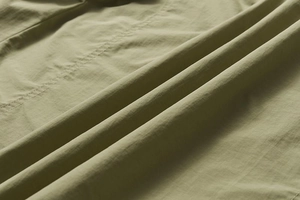 Détail macro du tissu vert olive d'un gilet d'extérieur avec coutures fines et texture