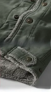 Detail of dark army green jacket featuring thick grey fleece lining and fashion metal button