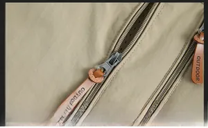 Detail of outdoor jacket with dual zippers and leather pulls featuring outdoor logo