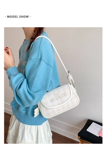 Detailed view of checkered shoulder bag with cute animal embroidery on a female model