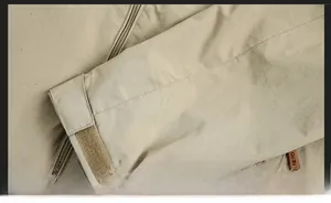 Detail of windproof sleeve cuffs with adjustable straps on beige outdoor jacket