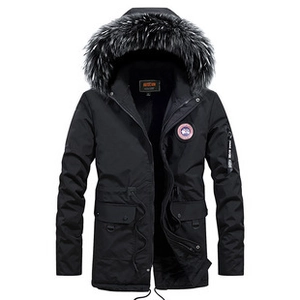 Detail of winter parka featuring large gray faux fur hood and red circular sleeve badge