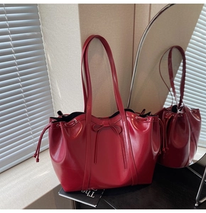 Detail of red patent leather tote bag featuring drawstring closure and metallic eyelets