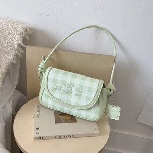 Detail of light green checkered shoulder bag with cute embroidery and biscuit pendant
