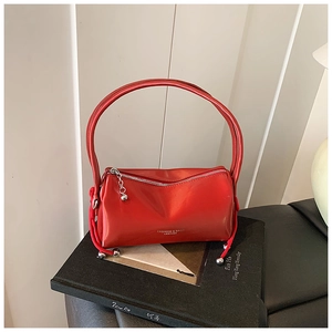 Detail of red glossy leather handbag featuring silver zipper and woven rope accents