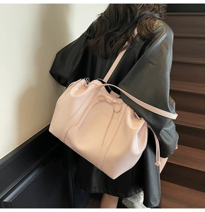 Detail of light pink patent leather tote bag featuring a decorative bow on the side