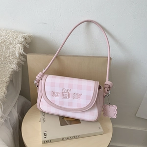 Detailed view of a pink plaid shoulder bag featuring cute embroidery and cookie pendant