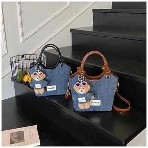 Gros plan sur les sacs seau en denim contrasté avec poignées en cuir et breloques
