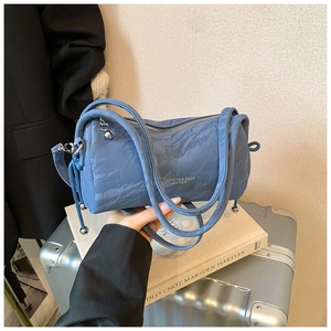 Detail of blue cylinder bag featuring pleated fabric and decorative metal ball charm