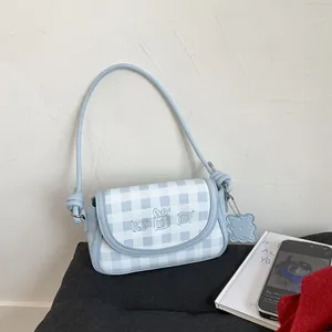 Close-up of blue plaid crossbody bag featuring cute cartoon embroidery and cookie charm